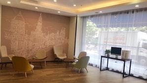 A modern waiting area with a cityscape mural, comfortable seating, a desk with a computer, and large windows. - Hanting Hotel Shanghai Macau Road (Shanghai)