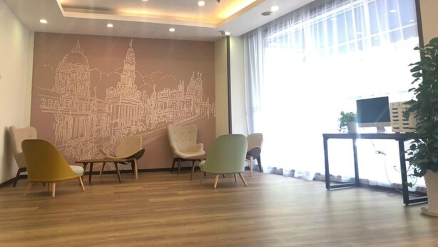 A room with a cityscape mural, wooden flooring, and a desk with a computer and a plant. - Hanting Hotel Shanghai Macau Road (Shanghai)