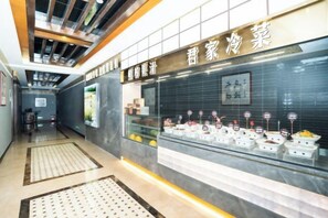 A corridor with a display of food items, a tiled wall with a sign, and a patterned floor. - Chuzhou King House Hotel. (Chuzhou)