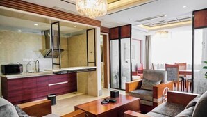A modern living room with a sofa, armchair, coffee table, and a dining area with a table and chairs. - Chuzhou King House Hotel. (Chuzhou)