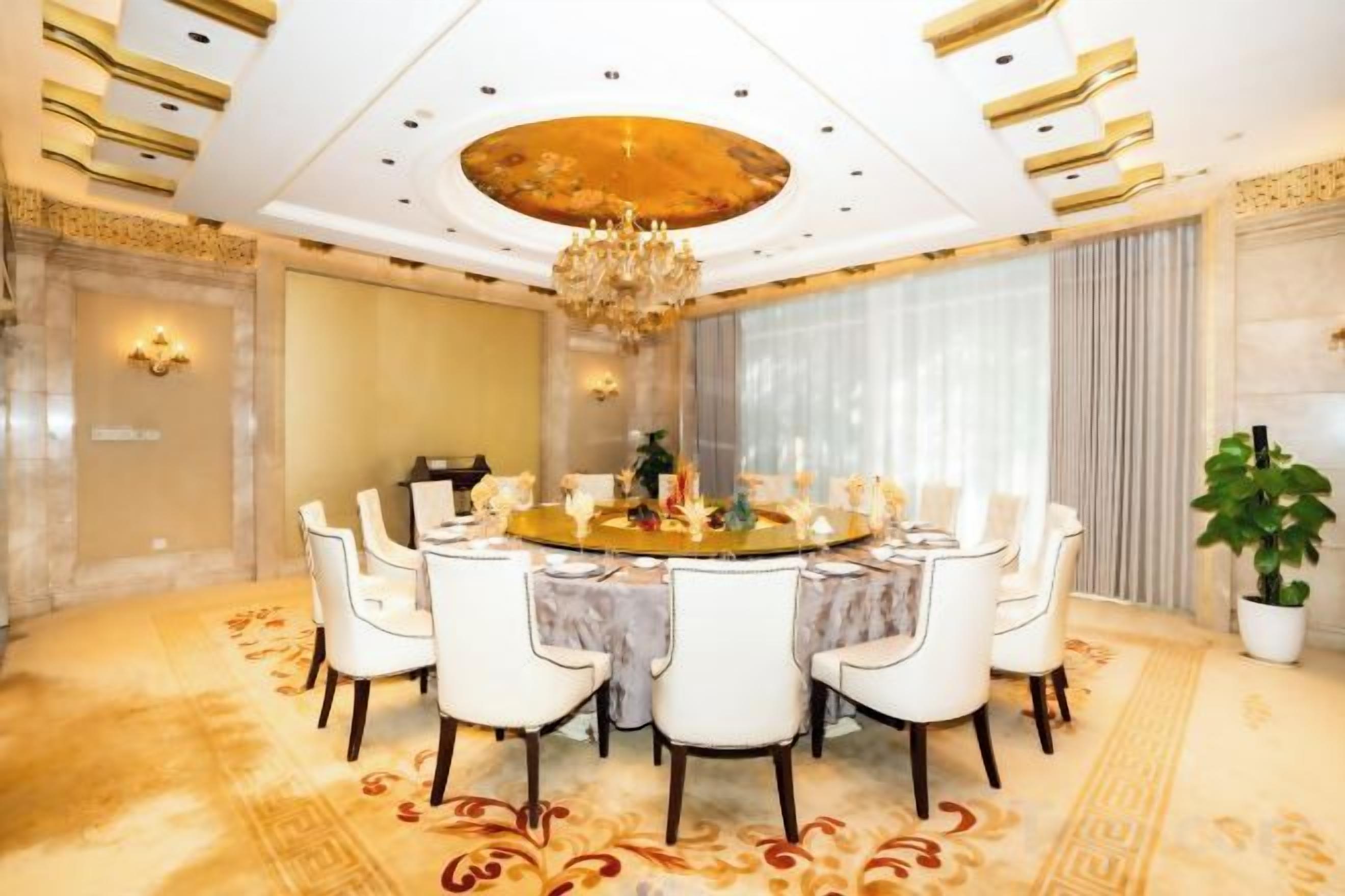 A formal dining room with a round table, white chairs, and a chandelier.
