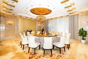 A formal dining room with a round table, white chairs, and a chandelier. - Chuzhou King House Hotel. (Chuzhou)