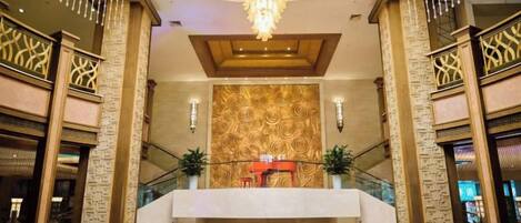 A lobby with a grand chandelier, a reception desk, and a circular seating area.