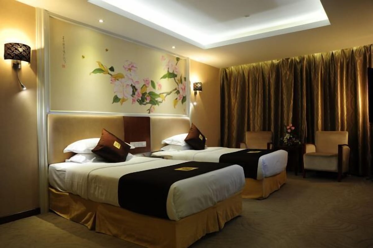 A hotel room with two beds, a large mirror, and a decorative wall with floral artwork.