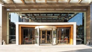A modern building entrance with a glass door and a wooden ceiling structure. - Chuzhou King House Hotel. (Chuzhou)