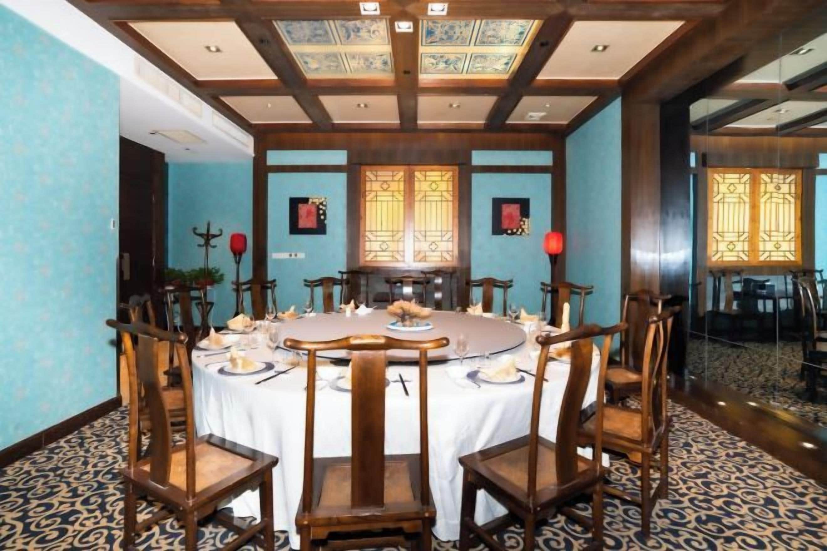 A dining room with a round table, chairs, and a chandelier.
