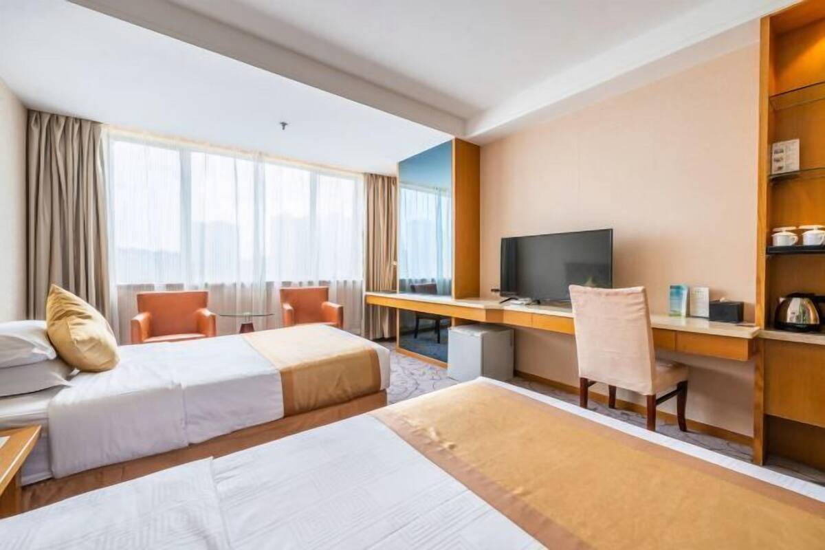 Hotellihuone, jossa on kaksi sänkyä, työpöytä, jossa on televisio, ja tuoli.