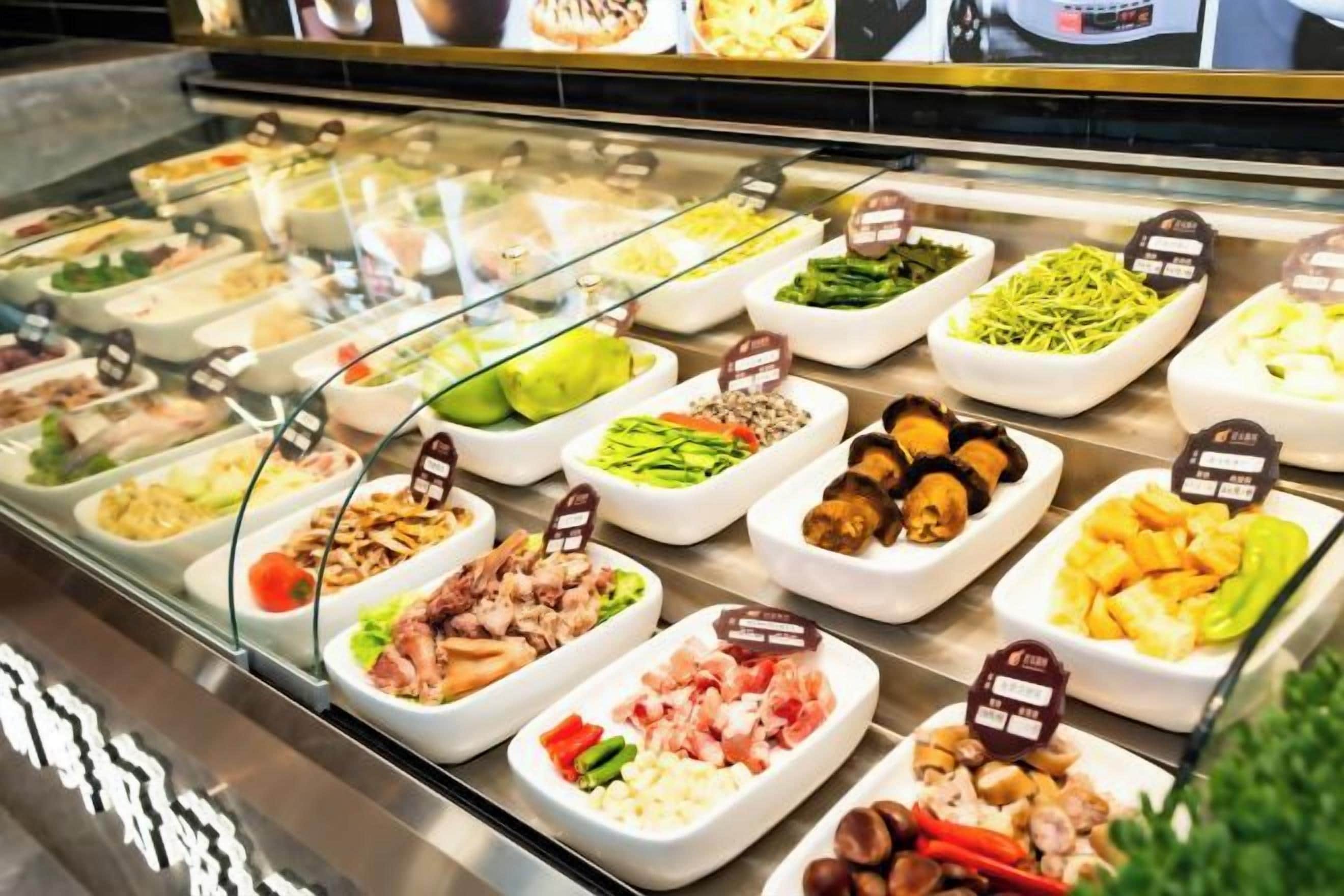 A buffet with various food items in white trays, each labeled with a sign.