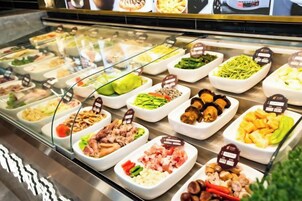 Un bufé con distintos alimentos dispuestos en fuentes blancas, cada una con una etiqueta.