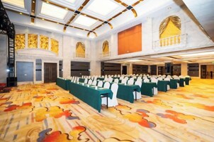 A large hall with rows of tables and chairs, high ceilings, and a patterned carpet.