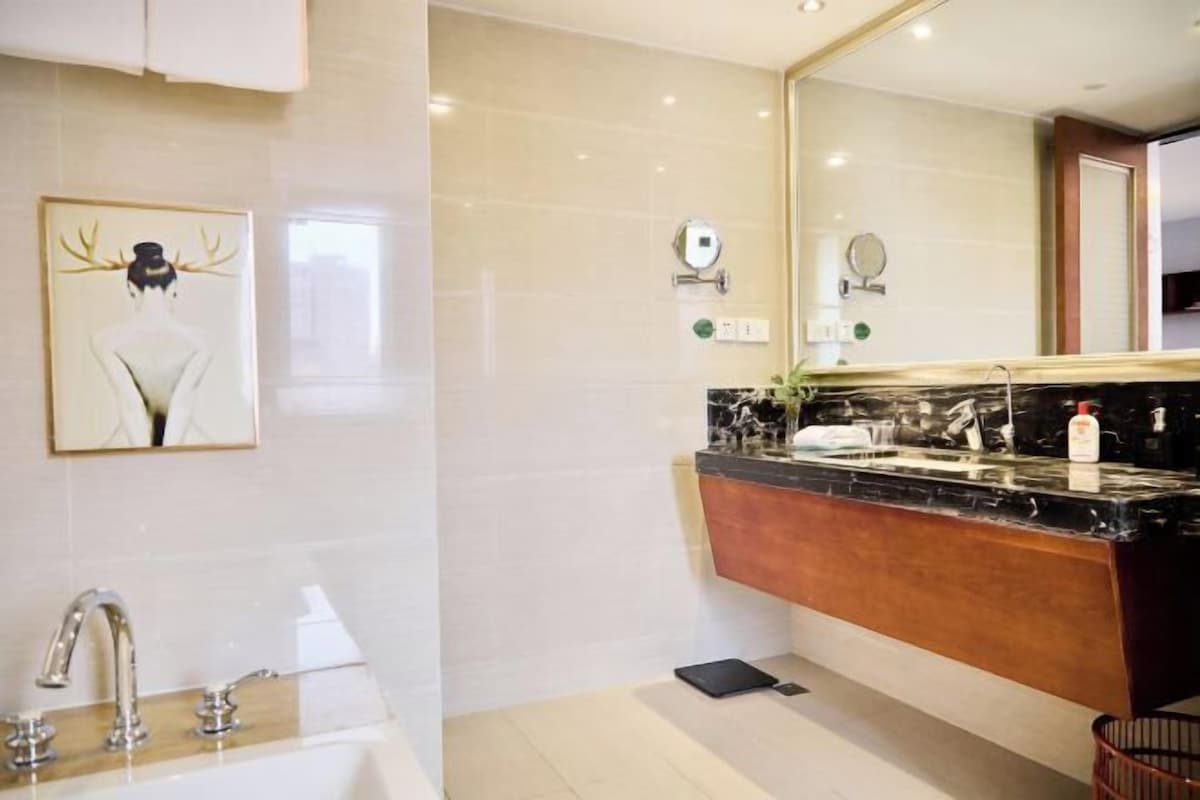 A modern bathroom with a large mirror, a marble countertop, and a wall-mounted sink.