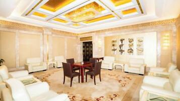A spacious room with a large chandelier, a dining area with a table and chairs, and a seating area with sofas.