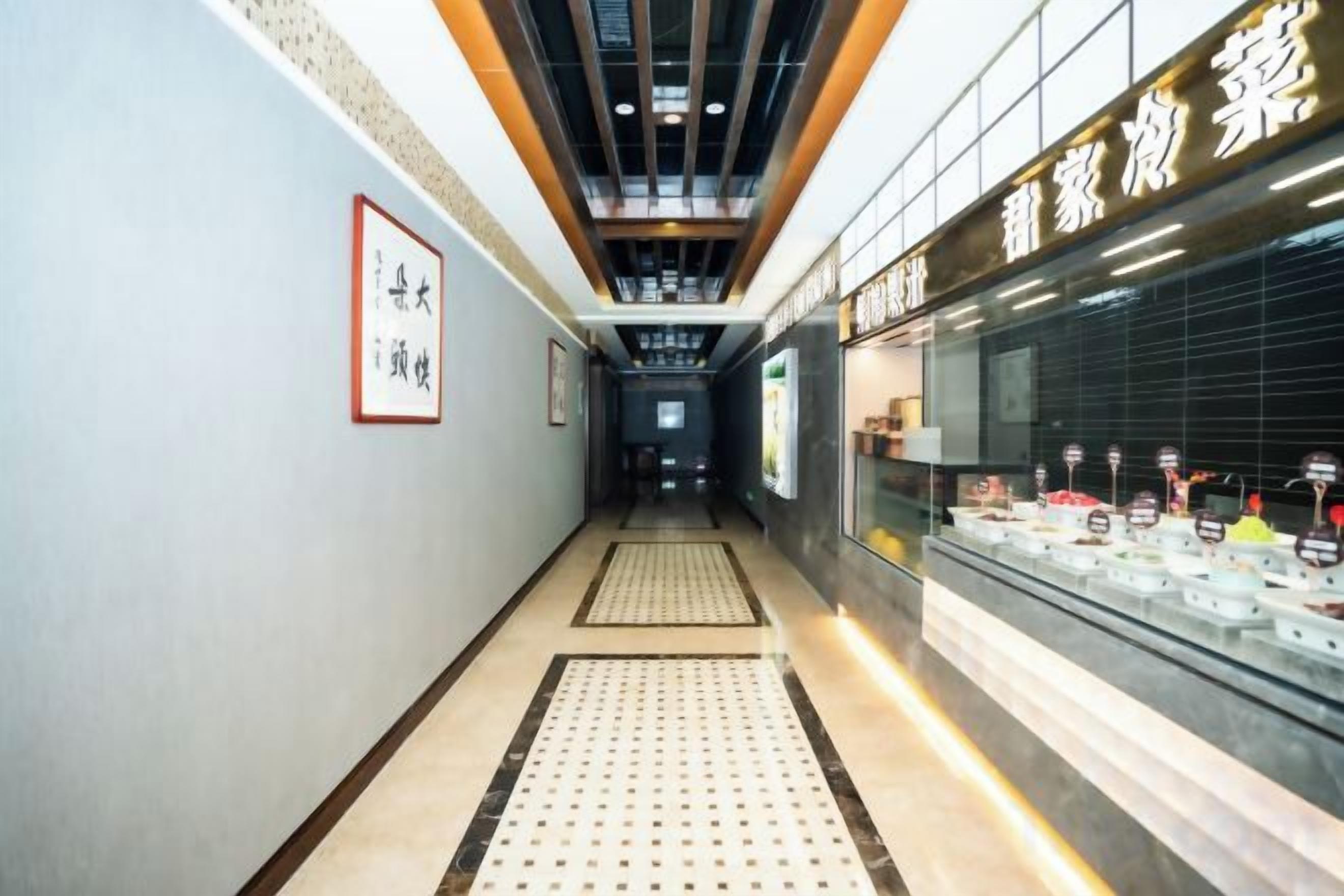A corridor with a tiled floor, a ceiling with wooden beams, and a display case with items on the right.