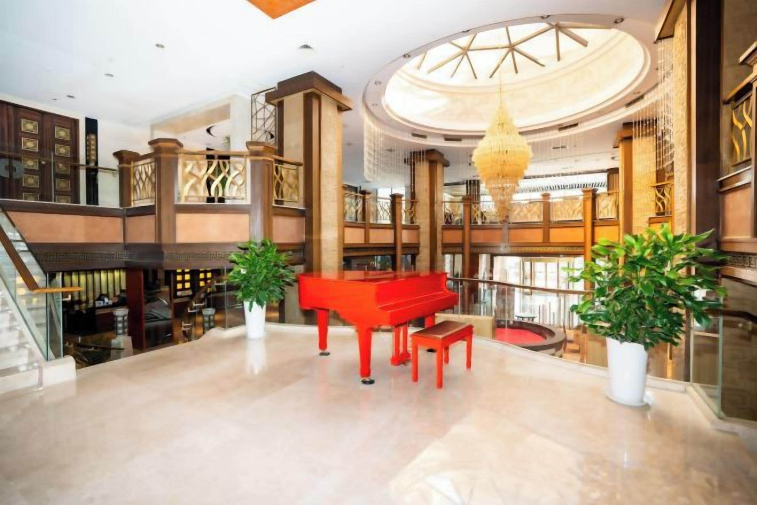 Um hall imponente com um piano de cauda, uma escadaria e um lustre grande.
