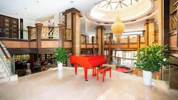 Um hall imponente com um piano de cauda, uma escadaria e um lustre grande.