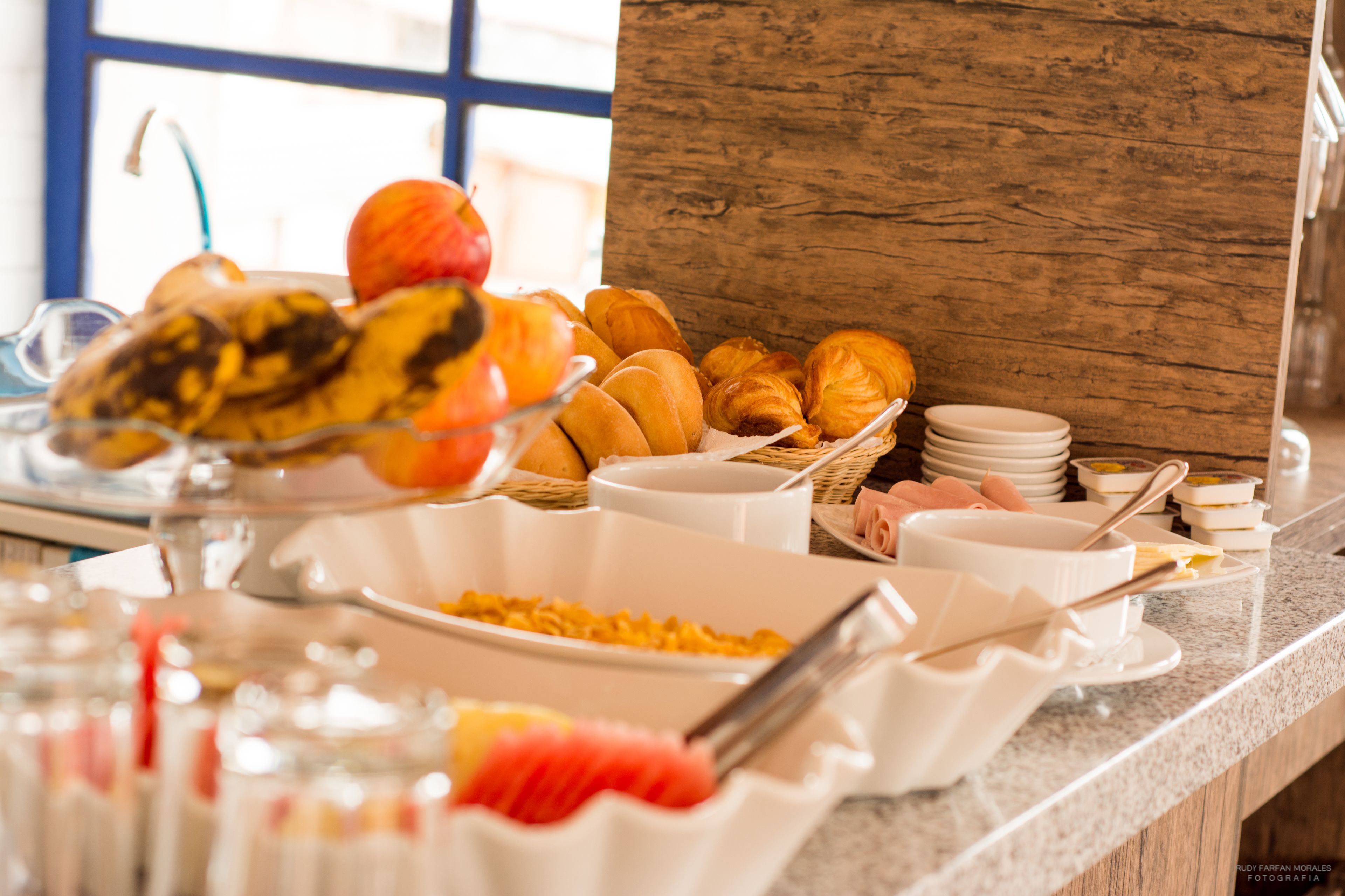 Un bufé con diversas opciones de desayuno, incluyendo frutas, bollería y platos.