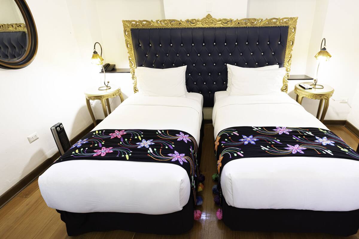 A double bed with a black and white headboard, two bedside tables with lamps, and a mirror on the wall.