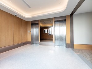 A modern elevator area with a clean, tiled floor and wooden paneling on the walls. - Ji Hotel (Shanghai)