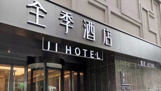 Das Ji Hotel mit moderner Fassade und Glastür.