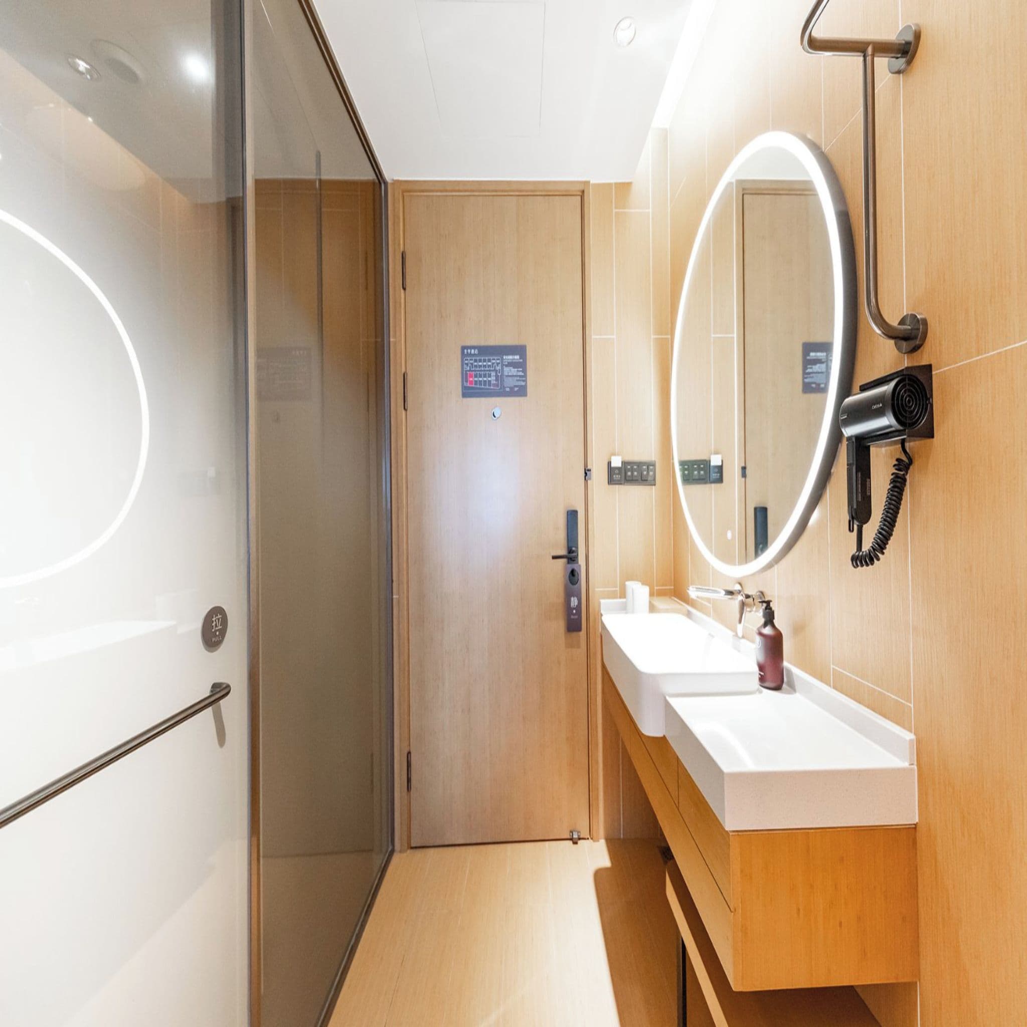 Un baño moderno con cabina de ducha de vidrio, tocador de madera con espejo y perchero.