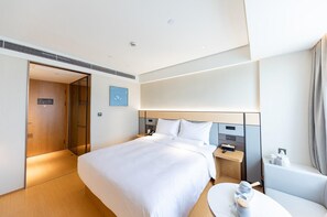 A hotel room with a bed, bedside table, and a small round table with a lamp. - Ji Hotel (Shanghai)