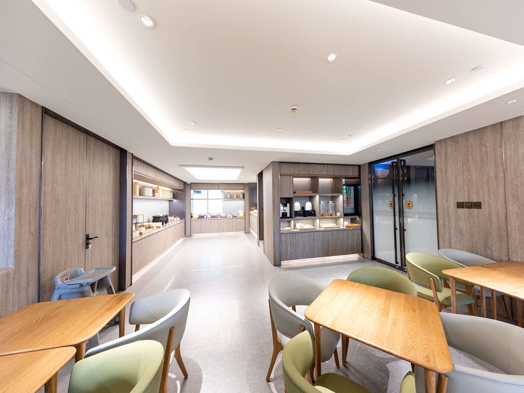 A modern hotel lobby with a central seating area, a kitchenette, and a refrigerator.