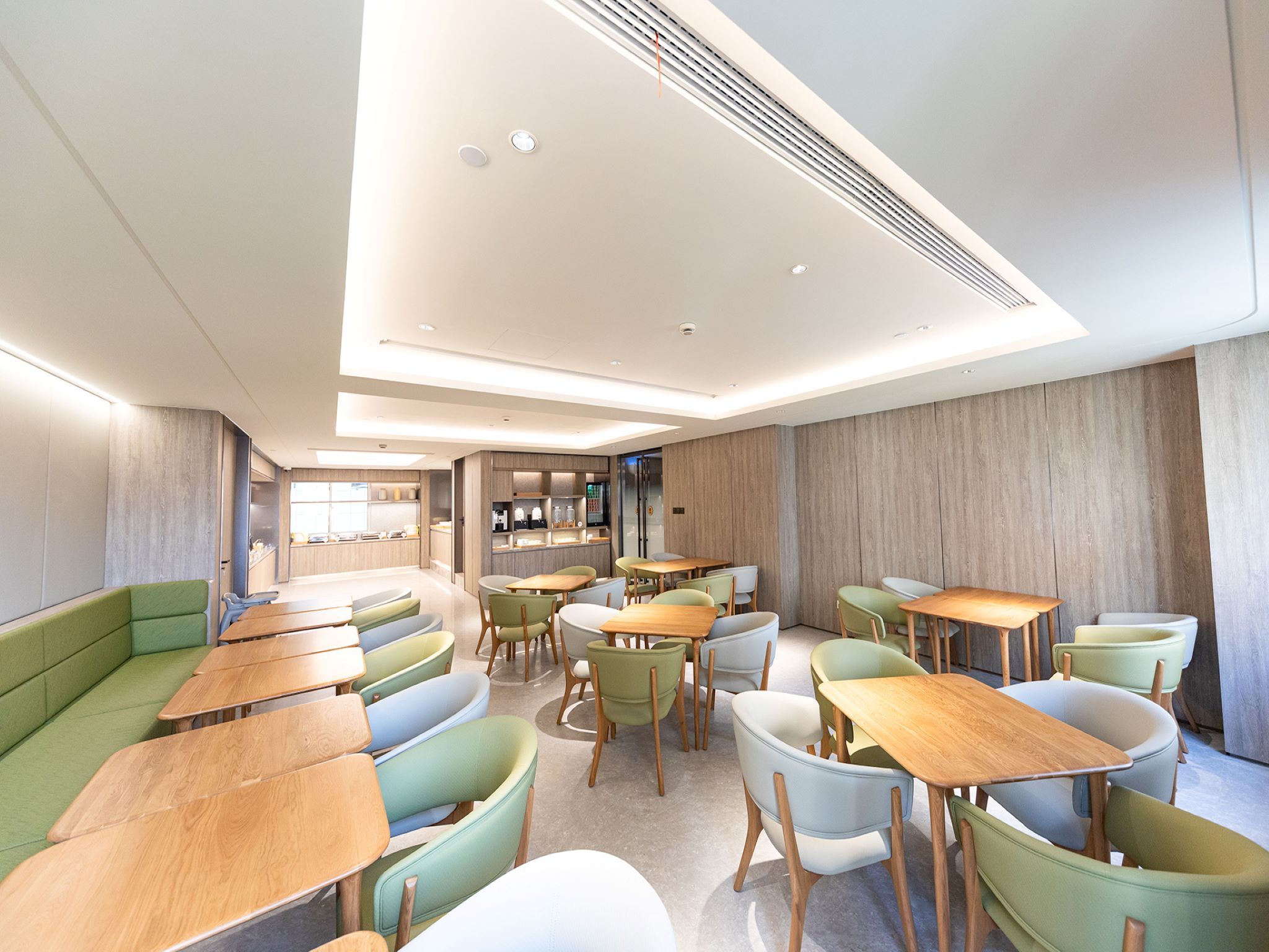 Un restaurant moderne avec des sièges verts et blancs, des tables en bois et un intérieur lumineux.