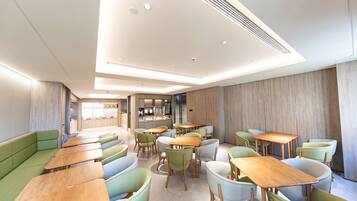 A modern restaurant with green and white seating, wooden tables, and a bright interior.