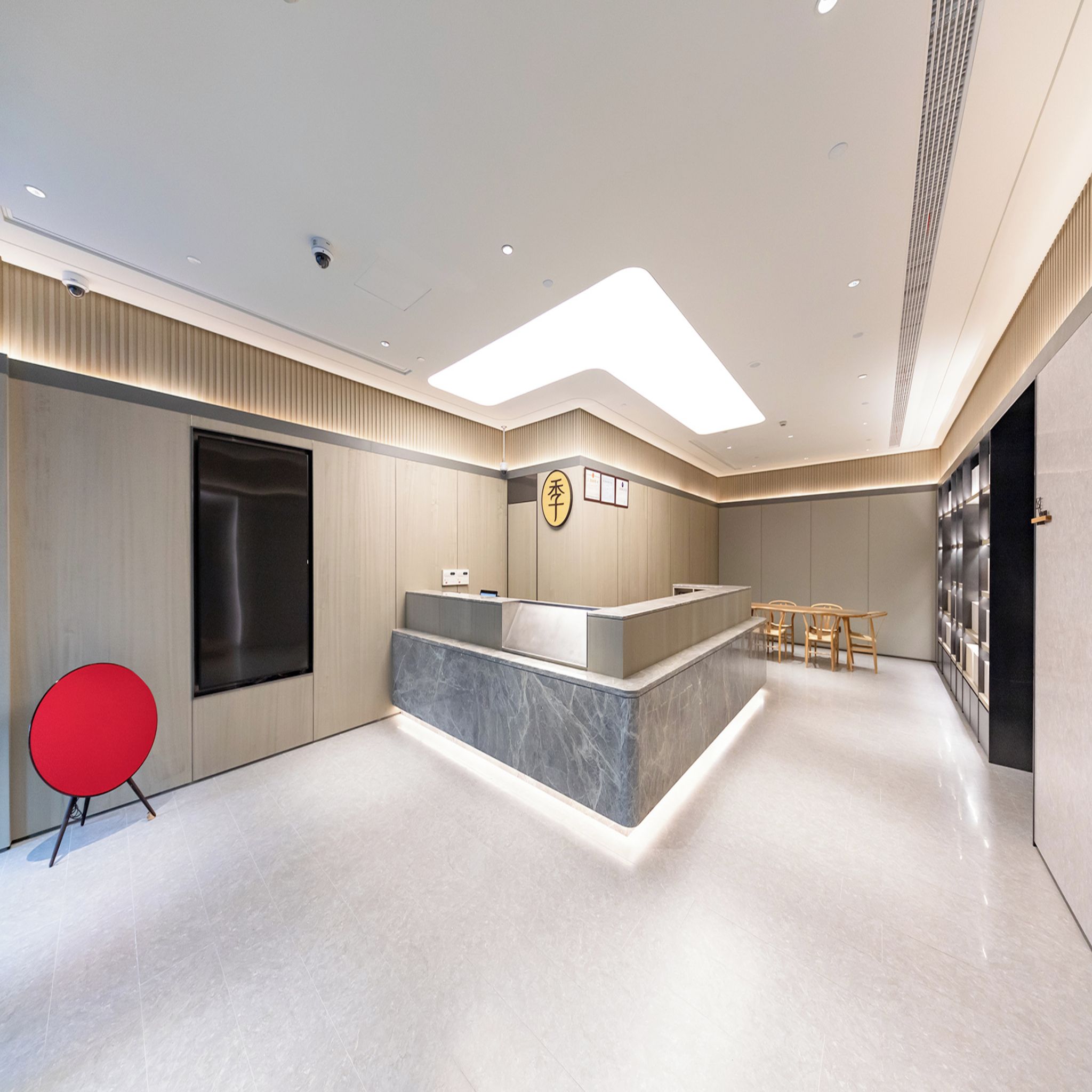 A modern reception area with a marble counter, a red chair, and a seating area with wooden chairs.