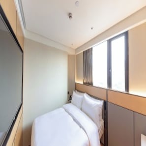 A modern hotel room with a large bed, a flat-screen TV, and a window with curtains. - Ji Hotel (Shanghai)