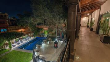 Zona de piscina en la azotea con vistas despejadas a la piscina, sillas de descanso y vegetación circundante.