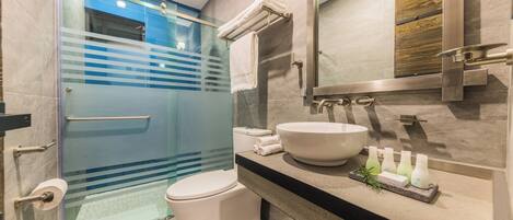 Een moderne badkamer met een douchecabine van glas, een wit toilet, een groot wastafel en een spiegel.