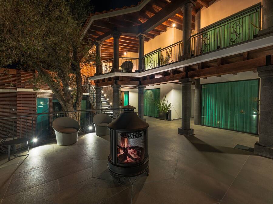 Un amplio espacio al aire libre con chimenea de piedra, asientos y un balcón cubierto con barandilla.