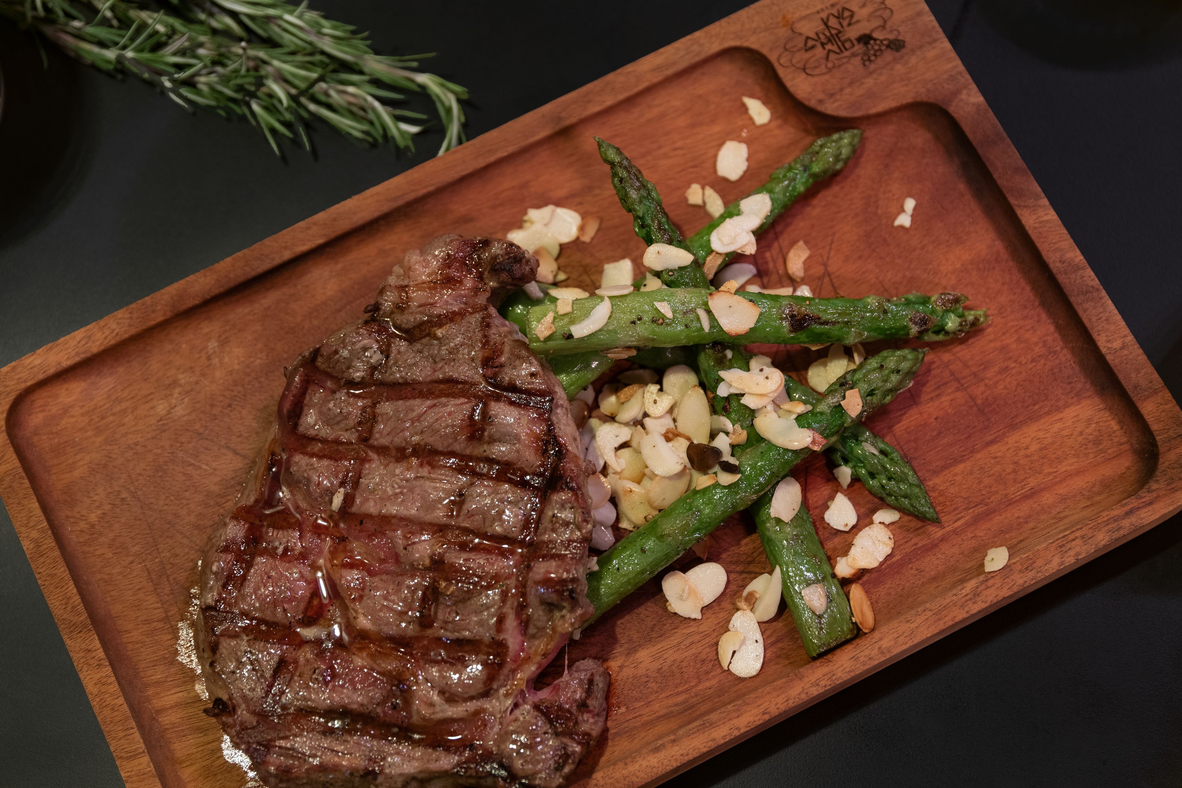 A wooden serving board with grilled steak and asparagus.
