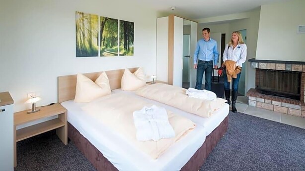 Ein Schlafzimmer mit einem großen Bett, einem Nachttisch, einem Kamin und einem Gemälde an der Wand.