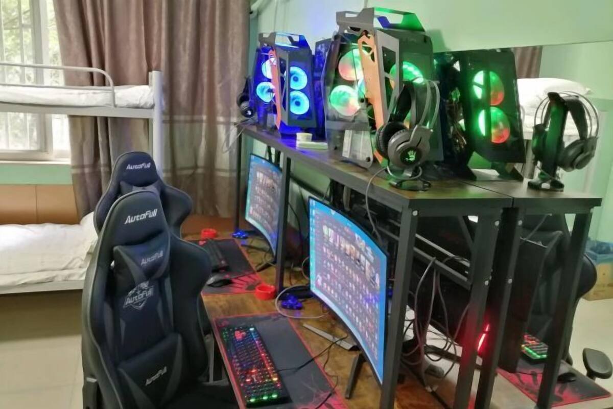 A gaming setup with multiple monitors, a gaming chair, and a bed in the background.