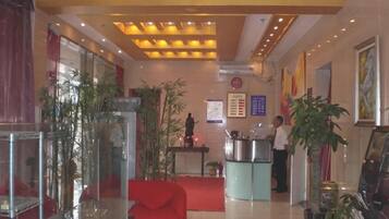 A reception area with a counter, chairs, and potted plants.