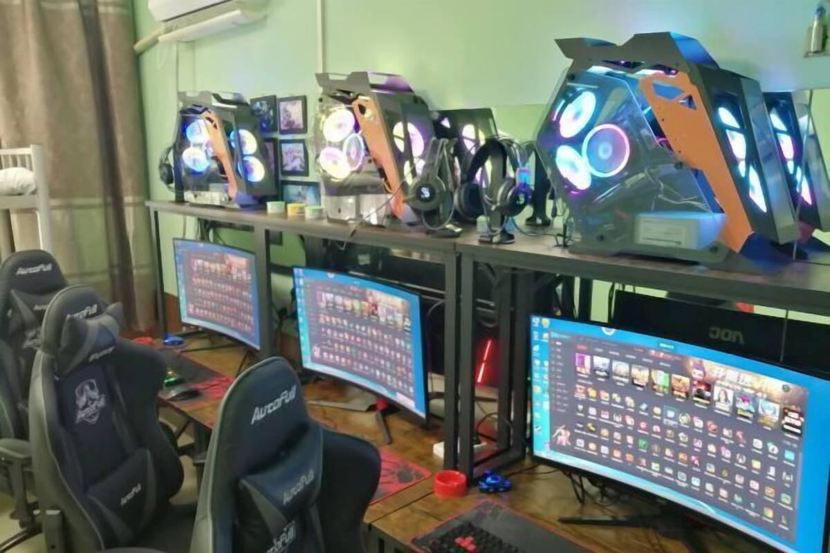 A gaming setup with multiple monitors, a gaming chair, and illuminated computer cases.