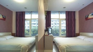 A hotel room with two beds, a TV, and a window with curtains.