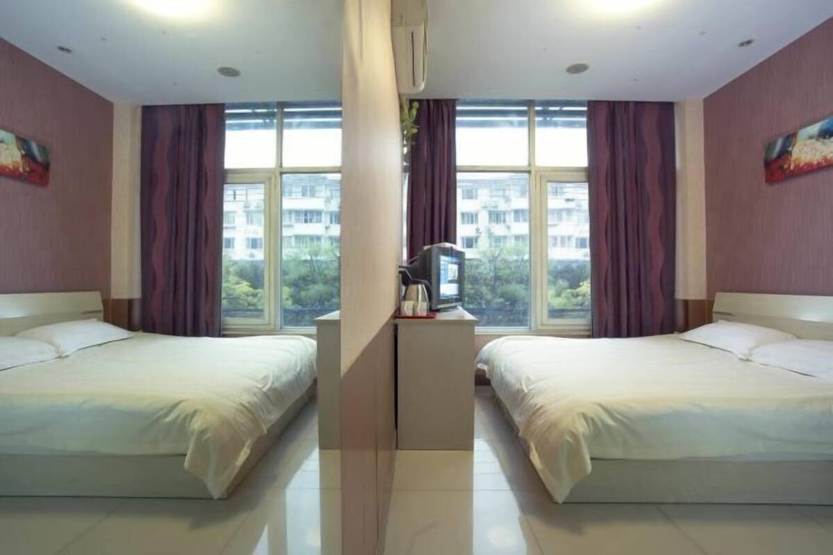 A hotel room with two beds, a TV, and a window with curtains.