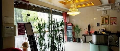 A reception area with a glass desk, a red sofa, bamboo plants, and a vending machine.