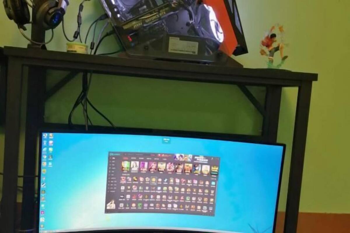A computer monitor on a stand with a desktop wallpaper, a pair of headphones, and a small figurine on the wall.