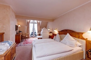 Habitación de hotel con dos camas, un escritorio, una silla y vistas al exterior.