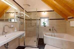 A modern bathroom with a glass-enclosed shower, a white sink, and a bathtub.