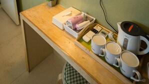 A hotel room with a bed, a bedside lamp, a mirror, a small table with a plant, a tray with mugs, and a coffee maker. - Hotel Tong Seoul Dongdaemun (Seoul)
