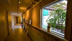 A hallway with wooden paneling, a window with a view of greenery, and framed pictures on the wall. - Hotel Tong Seoul Dongdaemun (Seoul)