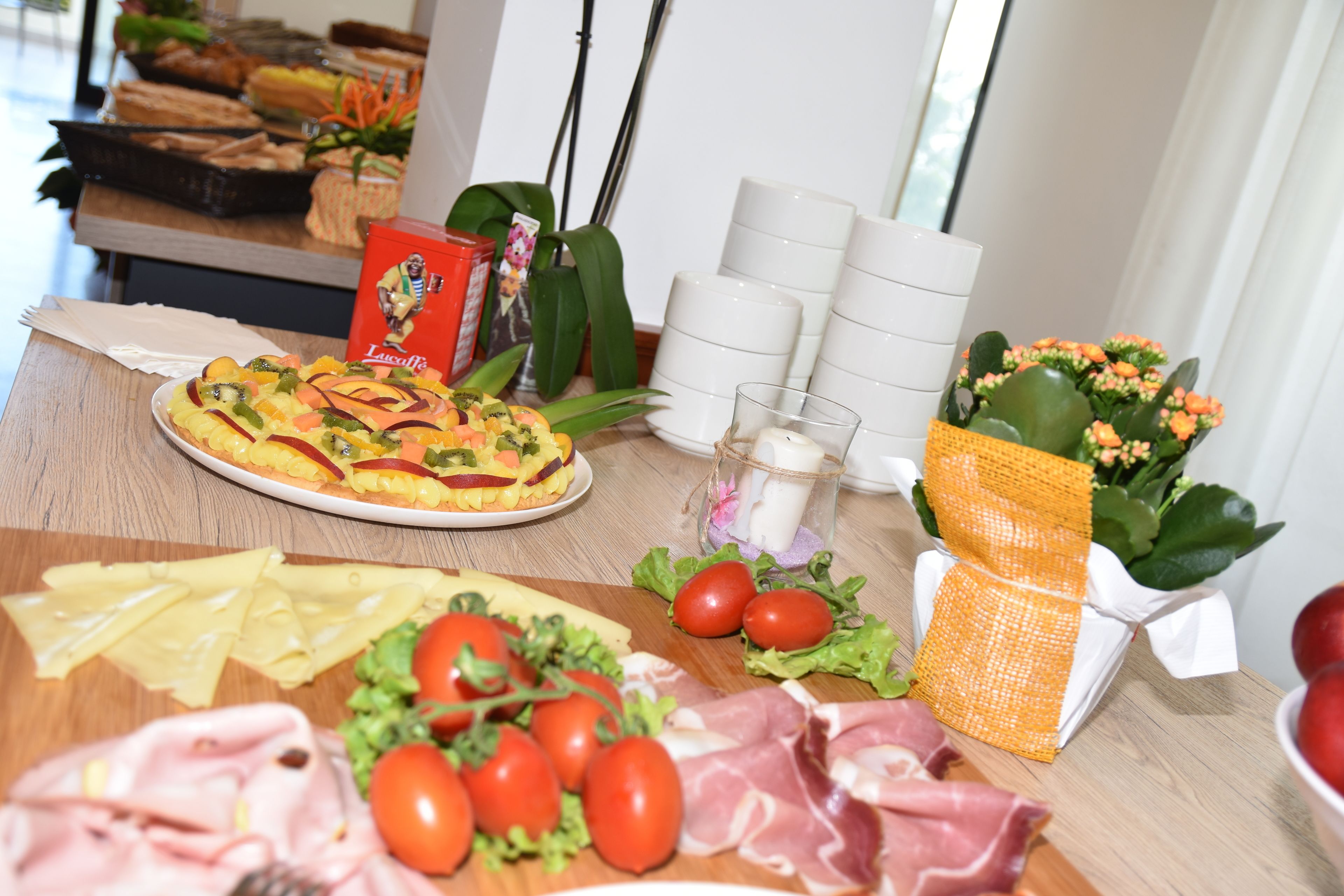 Une table de buffet proposant une variété de plats, notamment une salade de fruits, du fromage, des tomates et de la viande.