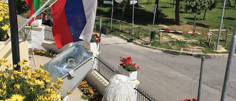 A building with multiple flags, a fountain, and flower beds.