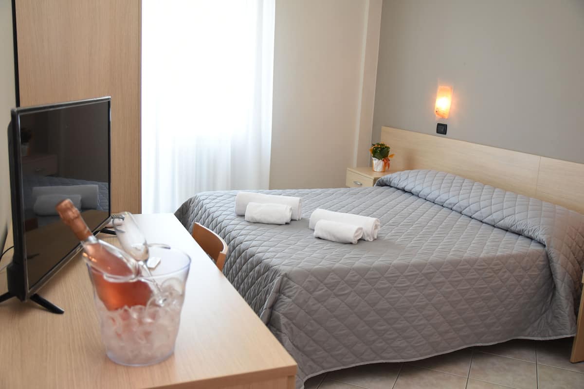 Una habitación de hotel con cama, mesita de noche y televisor.