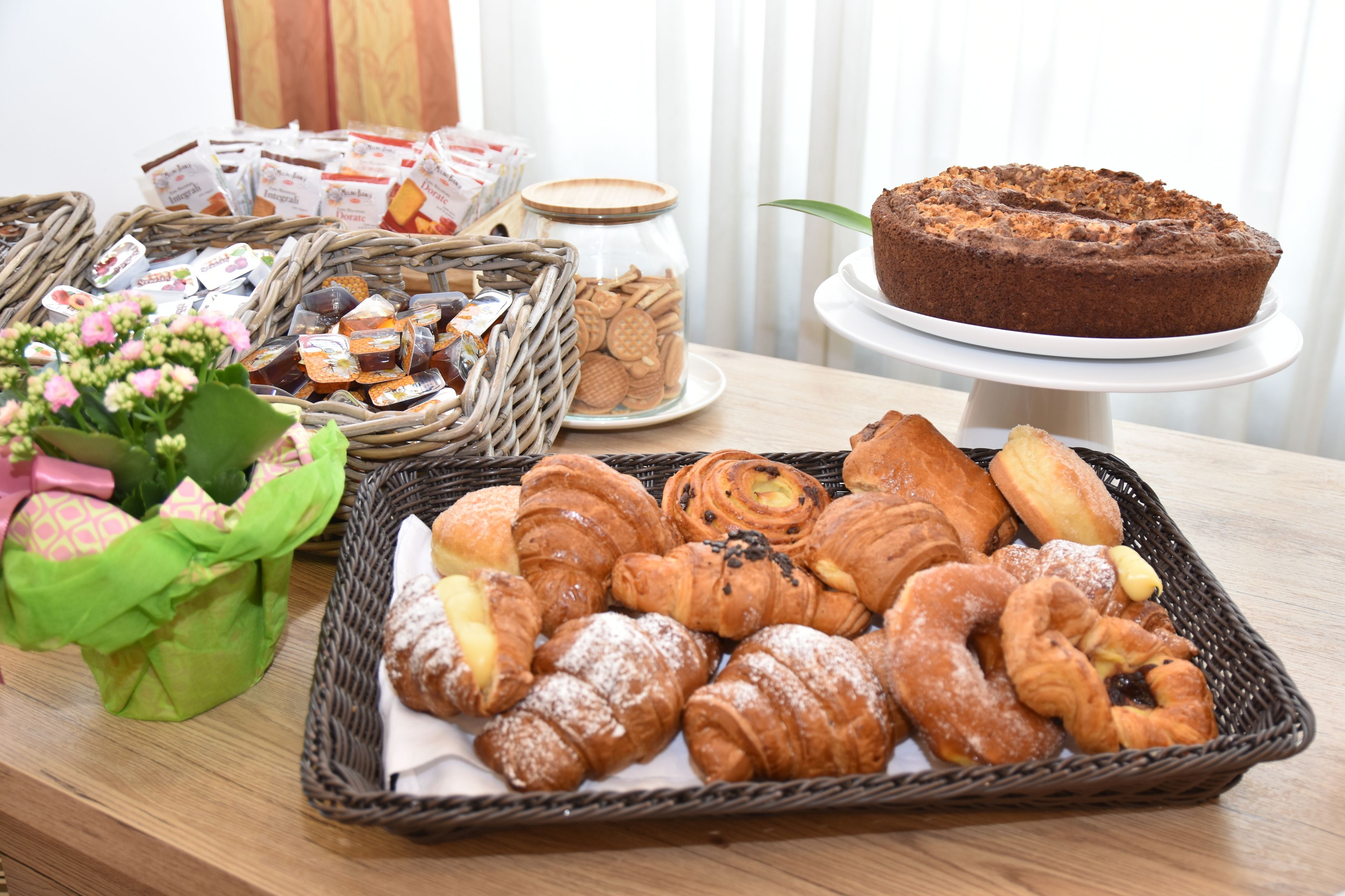 A table with various pastries and a cake, including croissants and a chocolate cake.